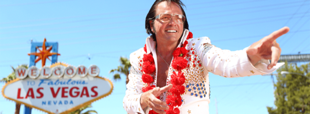 Elvis impersonator standing in front of the Las Vegas sign