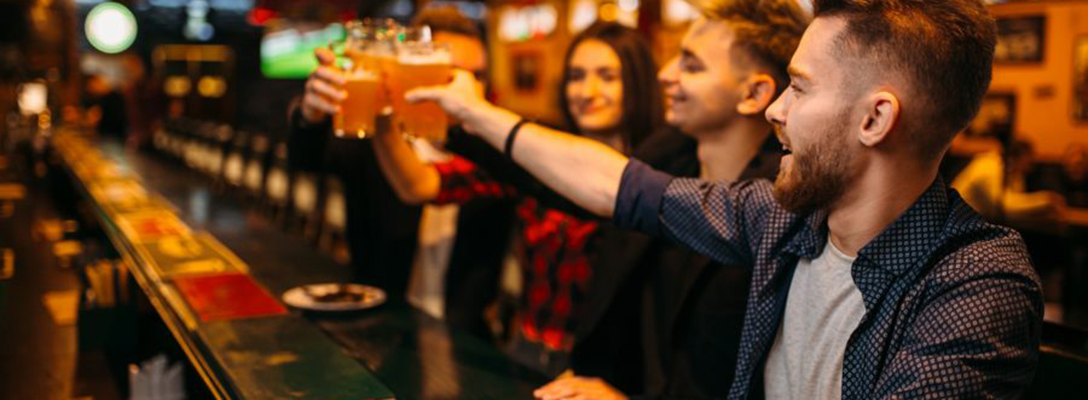 Group of friends raising their beers at the bar