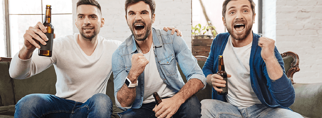 Three guy friends sitting on the couch and watching football