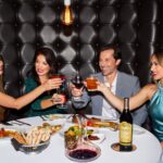 group having a cheers eating at a steakhouse with food and wine on the table